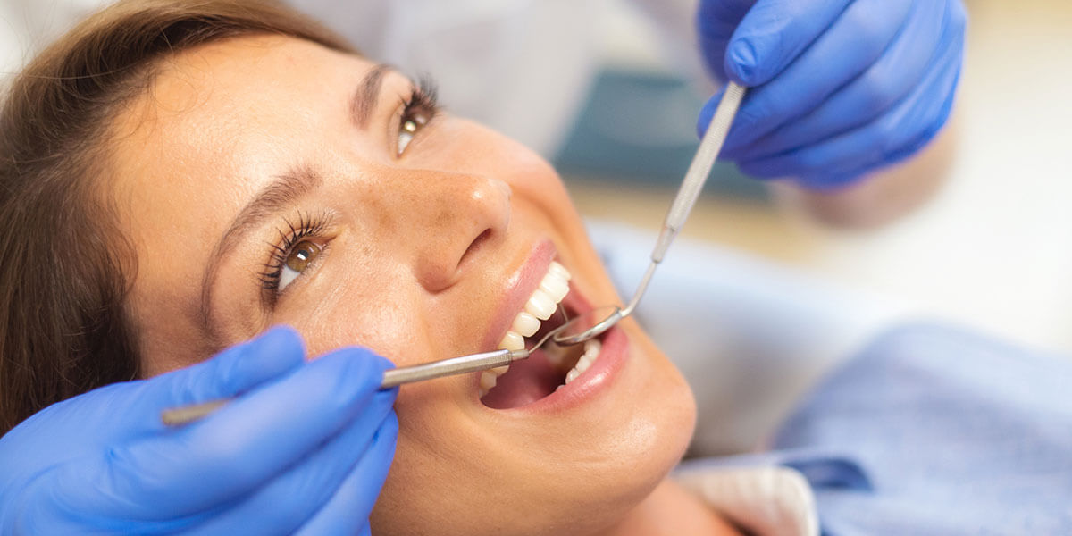 A female patient having her teeth examined by a dentist in a dental office.